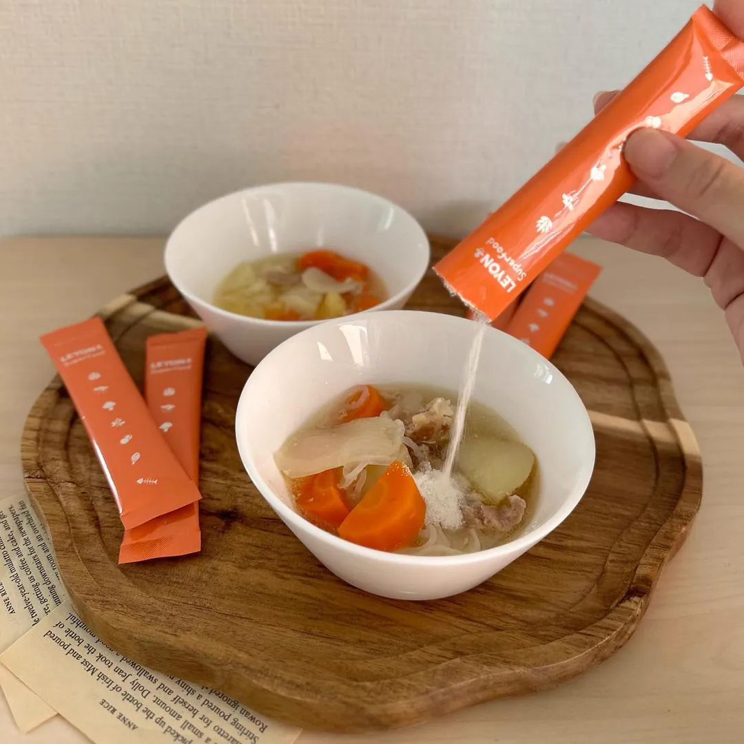 木のトレーのスープ2椀に粉を注ぐ様子